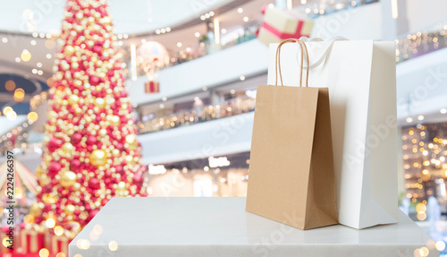 Christmas shopping bags on marble counter top with blurred festive mall background