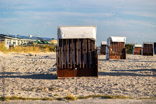 Traditional wicker beach chairs on sandy beach at the german north sea coast beach chairs on sand offering leisure and relaxation