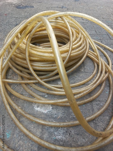 Close-up of a rolled-up translucent garden hose on textured concrete paving.