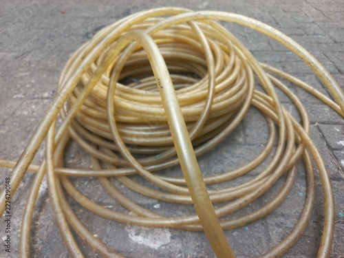 Roll of flexible plastic tubing or garden hose laid out on paving blocks.