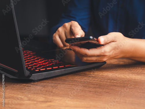 Person using smartphone beside laptop for communication