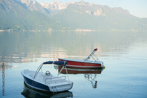 Two small moored boats on calm alpine lake water with peaceful mountain reflections