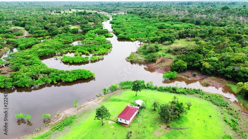 Aerial cinematic footage, Amazon basin in Brazil, revealing lush tropical vegetation and remote building, highlighting living conditions, biodiversity, and the natural landscape of the region