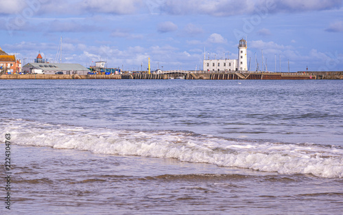 A beach with a pier and lighthouse in the background.