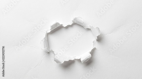 Torn hole in white paper background with ragged ripped edges and copy space