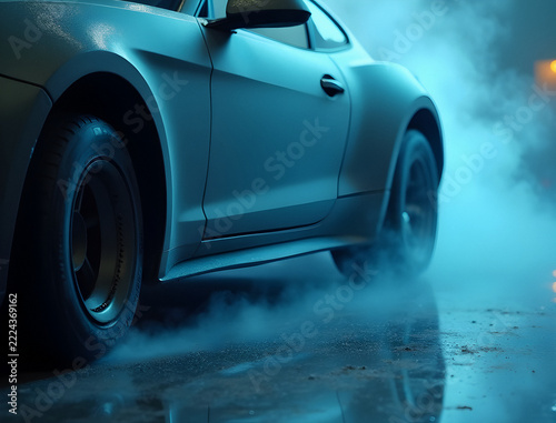 Gloved hand holding airless paint sprayer with mist and metallic sheen on black car hood in studio lighting