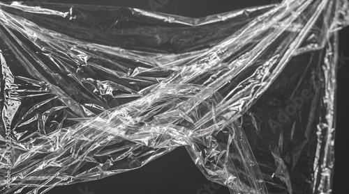 Crinkled transparent plastic wrap texture on dark background