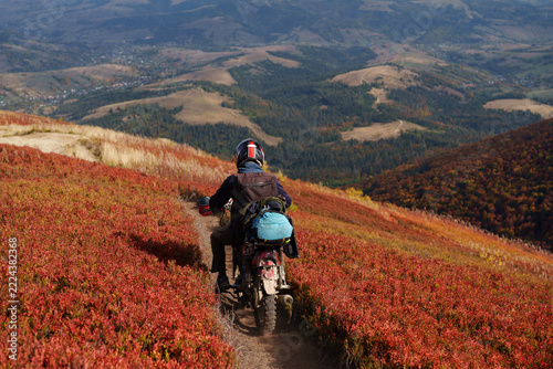 Back view of motorcyclist riding dirt bike on autumn Borzhava ridge trail.