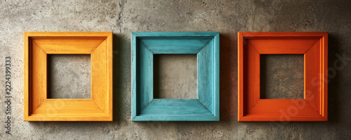 Colorful wooden square frames with rustic texture hang on rough concrete wall, creating vibrant and artistic display with warm and cool tones
