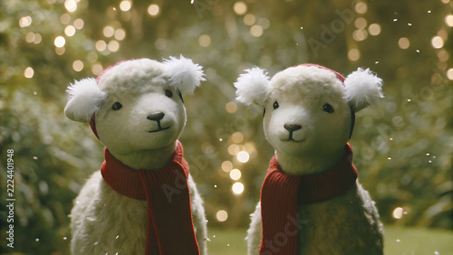 Two cute plush lambs wearing red winter scarves and hats for