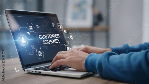 Hands typing on laptop displaying customer journey infographic with glowing icons in modern office setting