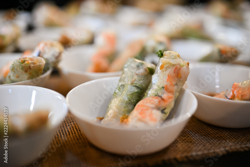 Vietnamese summer rolls with shrimp in white bowls at a buffet