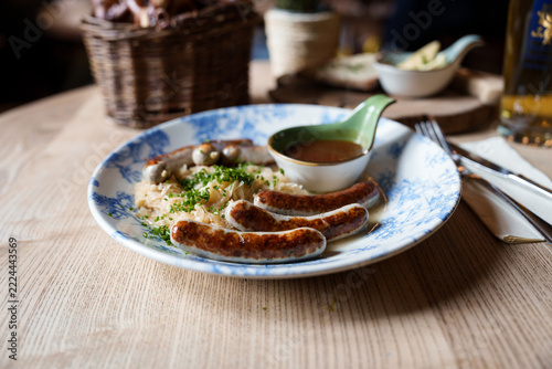 Grilled Nuremberg sausages with sauerkraut and mustard on a blue and white plate