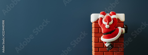 Santa Claus is climbing up the chimney on blue background with copy space. Christmas greeting card design. 3D Rendering, 3D Illustration