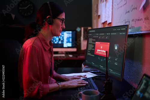 Middle aged Caucasian woman monitoring cybersecurity data on computer screen in office. Image suitable for IT security, data protection, cyber threat response advertising