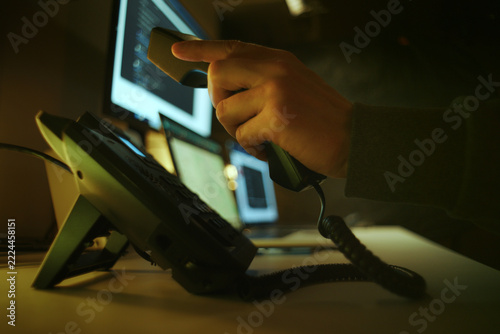 Scammer Making Telephone Call Among Computer Screens. Telephone Fraud Concept.