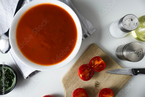 Fotografie Homemade tomato soup in a white bowl with fresh ingredients on table