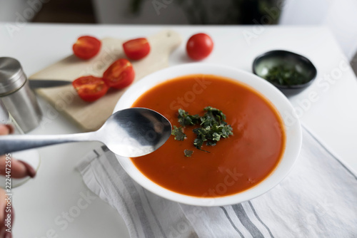 Fotografie Homemade tomato soup in a white bowl with fresh ingredients on table