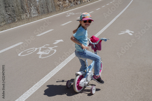 Child learning to ride bike with training wheels