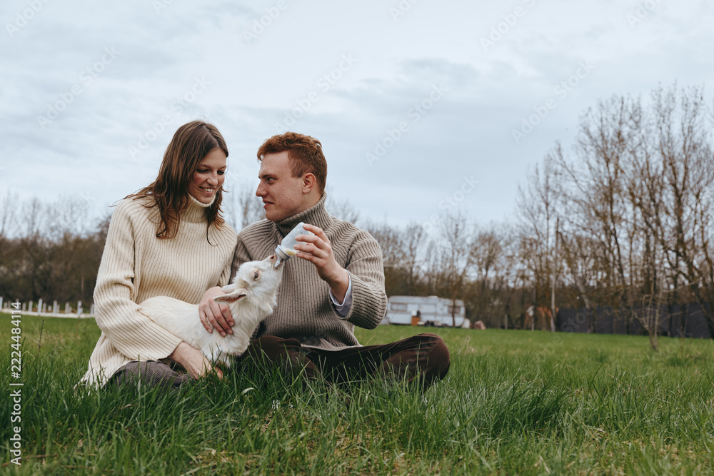 Fototapeta premium Couple outdoors with dog, affection and cozy atmosphere in a field setting, lifestyle moments of joy, grass underfoot, autumn light, candid smiles, serene countryside backdrop