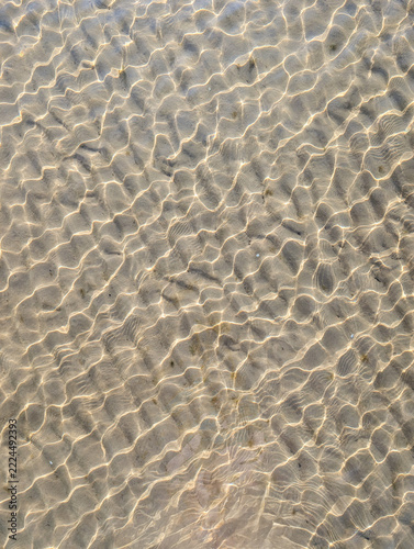 Natural texture background of sand ripples under transparent shallow sea water