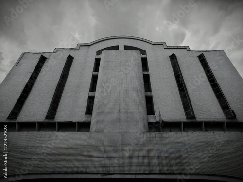 Dramatic gloomy photograph, Vintage or 70s-80s modern past facade building mystical photo style. timeless, overcast, cloud, imposing, dystopian, shadow, contrast, dark, modernist, imposing, storm