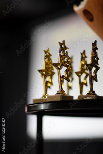 Golden star trophy awards on a dark blurred background. Concept of success, victory and recognition.