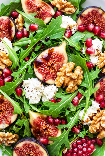 Detail of a fig salad with arugula, pomegranate seeds, cheese and walnuts. Mediterranean Diet Day
