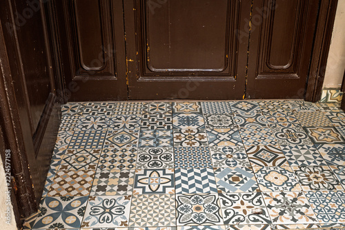 Vintage patterned hydraulic mosaic floor tiles near wooden door