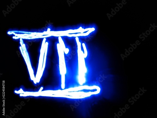 A blue neon light roman seven numeral drawn in light painting technique stands out against a pitch black backdrop. This abstract glowing electric digit is ideal for countdown and creative banner.
