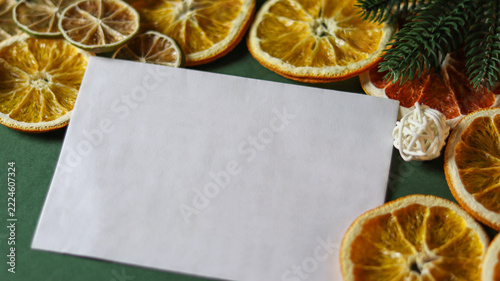greeting card mockup with blank paper. Dried fruit slices and blank card on green background for festive decoration