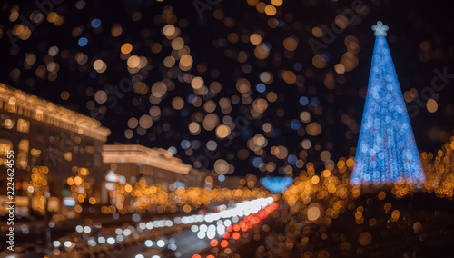Beautiful Defocused Christmas Tree and City Lights at Night with Bokeh Snowflakes