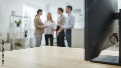 Empty Wooden Desk in Modern Office with Blurred Business People Collaborating in Background
