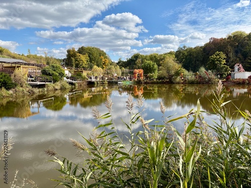 Scenic view of a calm lake with cloud reflection, autumn forest, and resort terrace