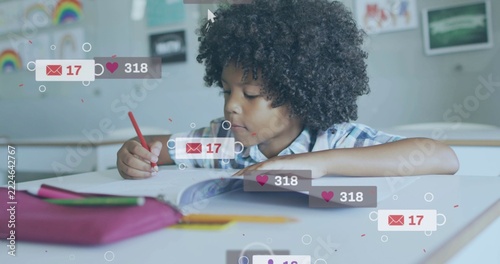 Writing student in plaid shirt at school desk, holding red pencil in workbook with overlay icons