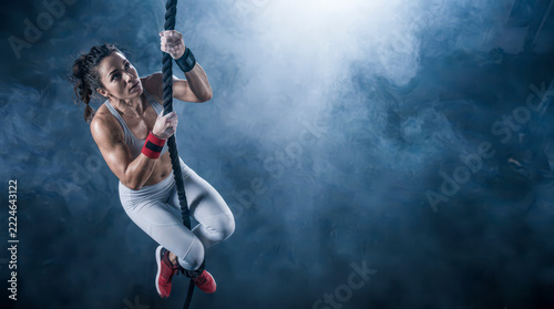 Determined woman climbing rope during intense gym workout