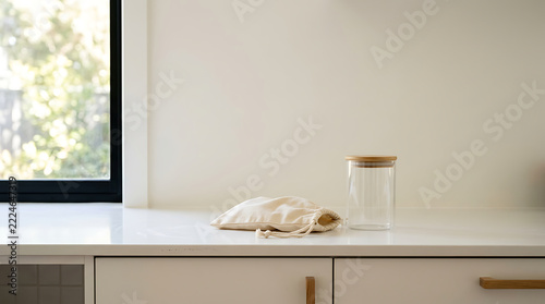 A serene kitchen countertop with a clear jar and a cloth bag by the window