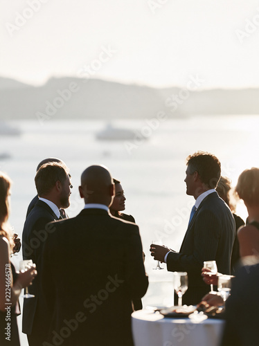 Corporate reception with professionals networking over drinks beside a waterfront view