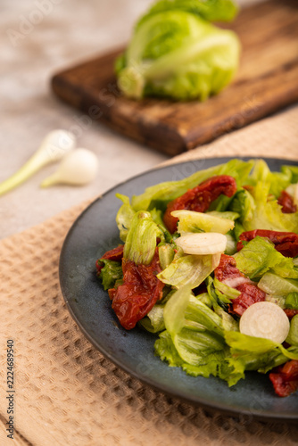 Mixed salad with lettuce, tomatoes, onion on blue plate on brown concrete. side view, close up, selective focus