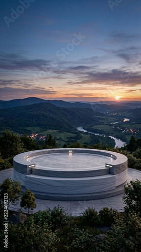 Modern circular observation deck overlooking a serene river valley at sunset offering panoramic mountain views