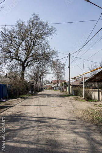 Rural village road with utility poles and gas infrastructure, Almaty region