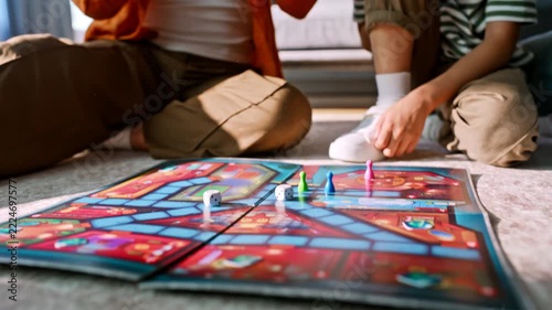 Closeup hands moving game piece board. Mother son playing floor living room.