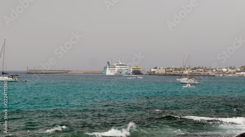A body of water with several boats including a large cruise ship and a coastline with buildings in the background