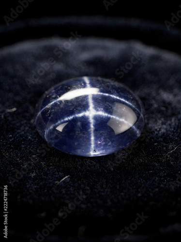 Blue star sapphire cabochon with asterism on black velvet cloth
