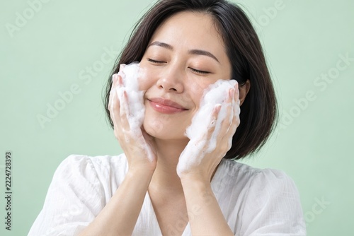 Woman Holding White Cleansing Foam to Her Cheeks against Pale Mint