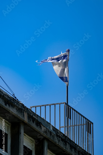 Torn flag flying above a weathered rooftop railing