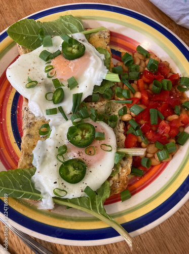 Plate of breakfast food with toast and poached eggs and various fresh vegetables