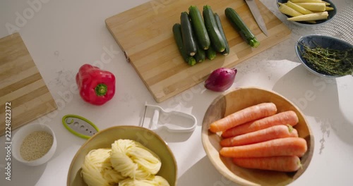Camera is pulling back revealing cutting board with zucchinis and knife on island, showing prep