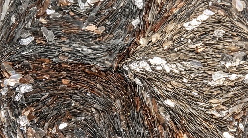 Natural mica mineral formation with layered flakes and metallic sheen in brown, gray, and silver