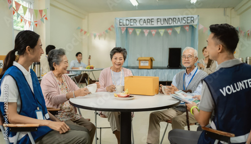 Volunteers and elderly people sitting together at a community elder care fundraiser event.